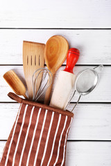 Set of kitchen utensils in mitten on wooden background