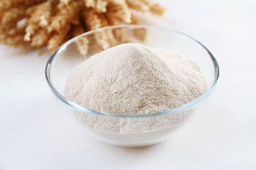 Glass bowl with flour and ears isolated on white