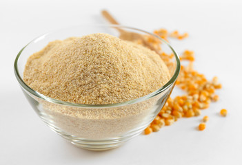 Glass bowl with flour and corn grains isolated on white