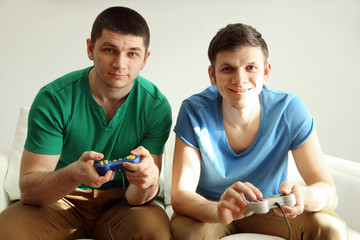 Two handsome young men playing video games in room