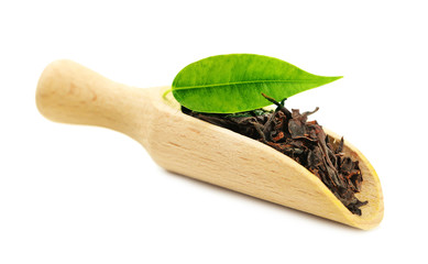 Wooden scoop with black tea with leaf isolated on white