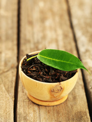 Black tea with leaf in bowl on old wooden table