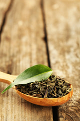Green tea with leaf in spoon on old wooden table