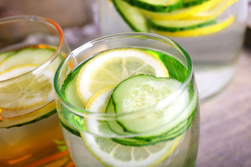 Fresh water with lemon and cucumber in glassware in wooden