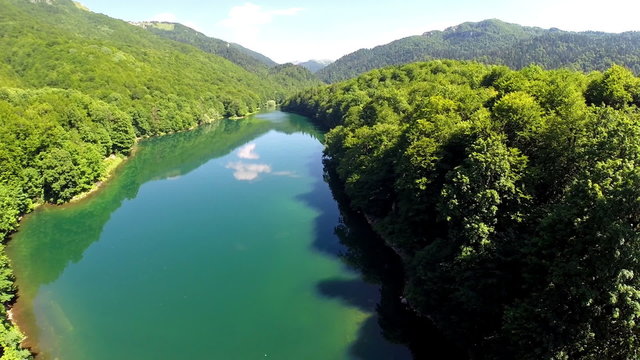AERIAL: Flight over lake with forest around