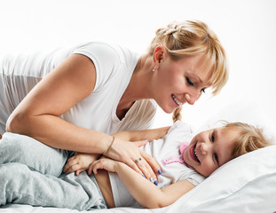 Obraz na płótnie Canvas Woman and daughter lying in bed smiling
