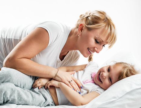 Woman and daughter lying in bed smiling