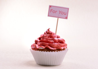 Delicious cupcake with inscription on table on beige background
