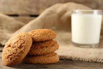 Tasty cookies and glass of milk on rustic wooden background