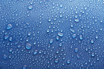 Water drops on glass on blue background