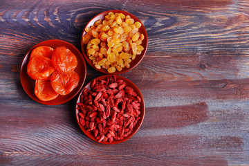 Dried fruits in small plates on rustic wooden table background