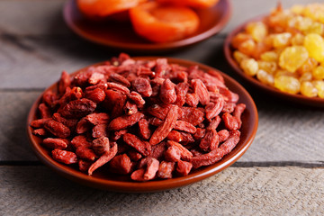 Dried fruits in small plates on wooden planks background