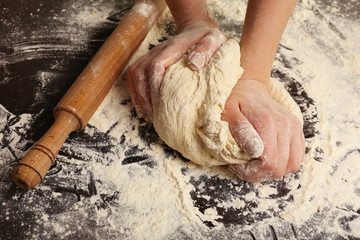 Making dough by female hands on wooden table background