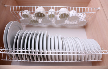 Fototapeta na wymiar Clean dishes drying on metal dish rack on shelf