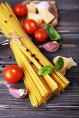 Raw pasta with cheese and vegetables on wooden background