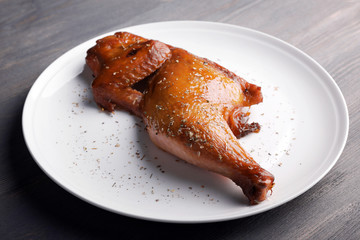 Smoked chicken leg on plate on wooden background