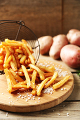 Tasty french fries in metal basket on wooden table background