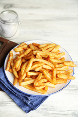 Tasty french fries on plate, on wooden table background