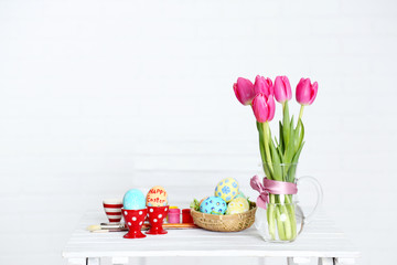Table with flowers, decorated Easter eggs and brushes,