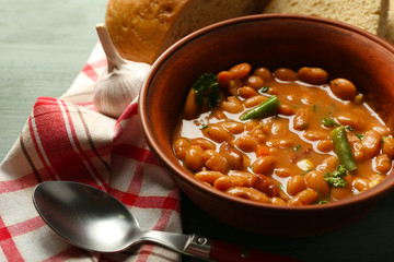 Bean soup in bowl on napkin, on wooden table background