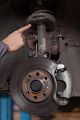 Mechanic hand pointing at a car shock absorber