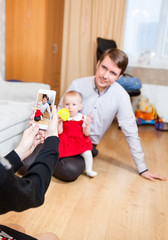 Mother photographing husband and daughter with mobile phone