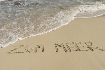 Text ZUM MEER am Sandstrand mit Wellen