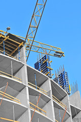 Crane and building construction site against blue sky