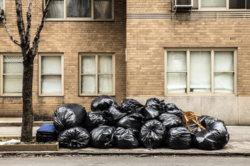 Plastic trash bags on curb outside city building