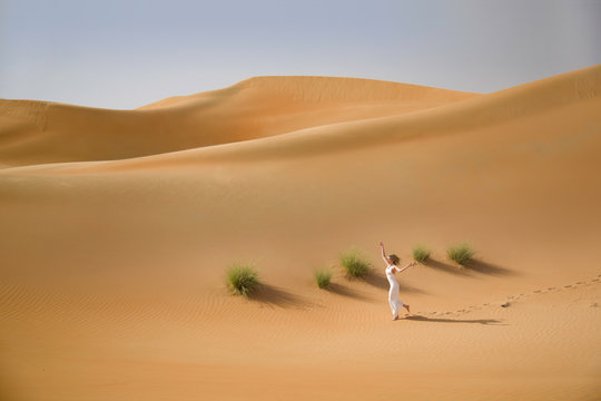 Beautiful sand dunes, a slim running woman in white dress