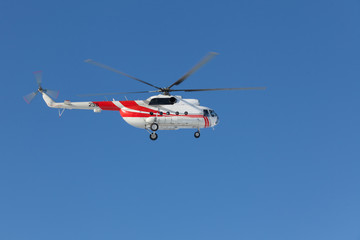 Fototapeta na wymiar Red and white helicopter flying in the blue sky