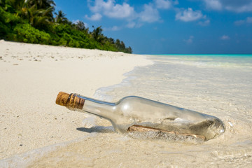 Message in a bottle washed ashore on a tropical beach.