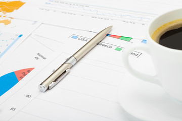 Coffee cup and pen over financial charts