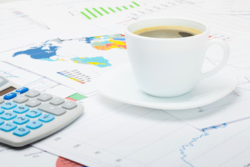 Coffee cup and calculator over financial charts