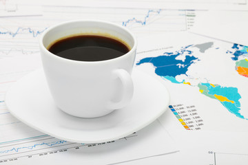 Coffee cup over world map and financial documents