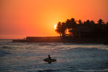 Surfer in the water during a sunset at Playa el Tunco, El Salvad