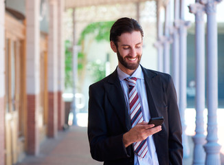 Friendly businessman smiling with mobile phone