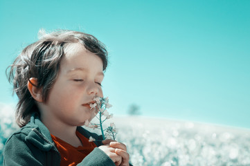 Little boy sniffs a flower