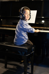 Little boy playing the piano and looking over shoulder