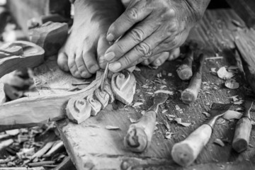 Hand of carver carving wood in blackand white color tone