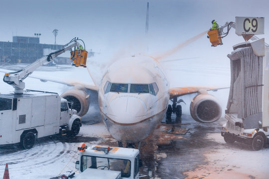 Airport attendant washing airplane in winter weather at an