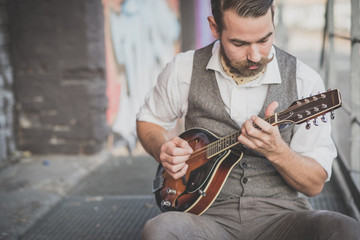 handsome big moustache hipster man playing mandolin - obrazy, fototapety, plakaty