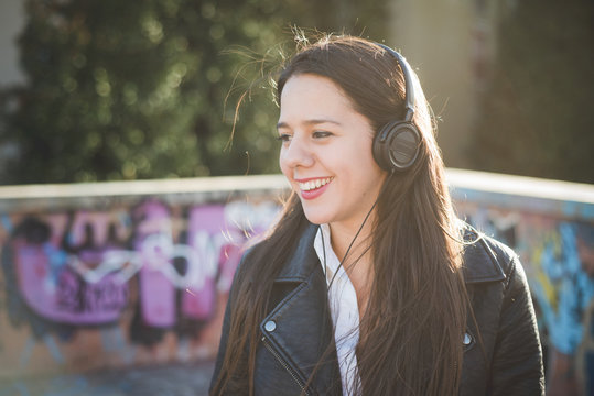 Smiling young woman listening to music outdoors