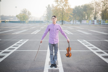 Portrait of young man with violin standing on street