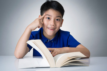 Little asian boy read a book and think about