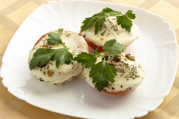 Tomatoes baked with mozzarella cheese on a plate.