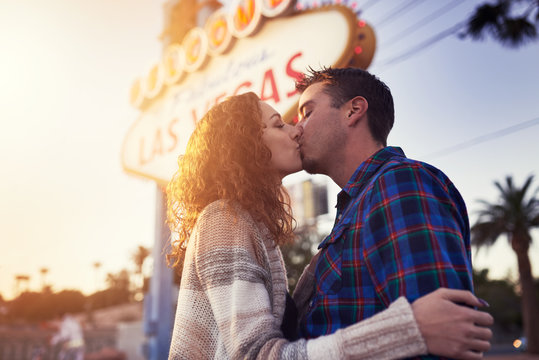 romantic couple kissing in front of vegas sign