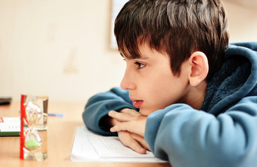 Obraz premium boy doing homework and looking on the hourglass