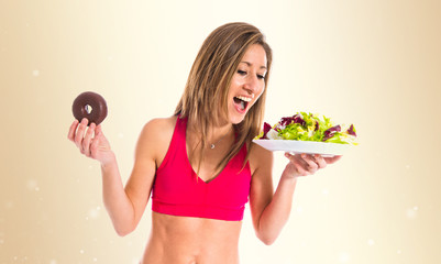 woman undecided between a donut and a salad