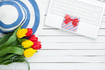 White computer and bouquet of tulips with gift